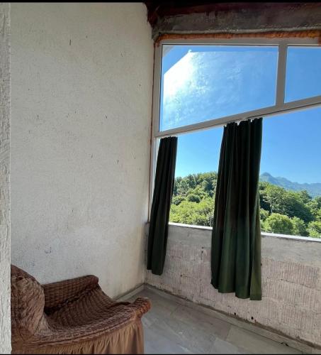 a window with green curtains in a room with a chair at APARTMENTS Mir in Virpazar