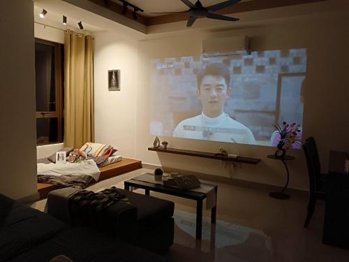 a living room with a man on a projection screen at Bali Melaka SeaView WaterPark 2-5Pax 5minJonker Projector in Melaka