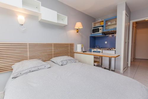 a bedroom with a white bed and a kitchen at Résidence Le Crystal Dinard Plage in Dinard