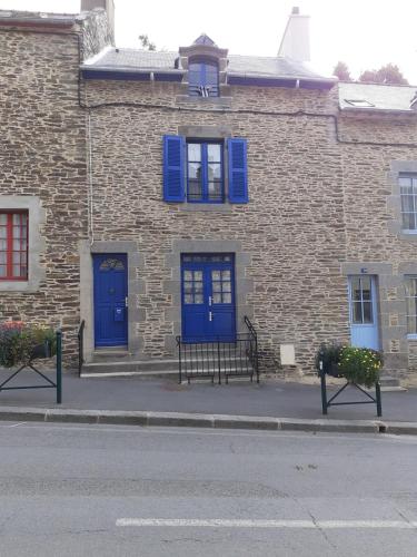 a brick building with blue doors and two benches at Maison de charme cancalaise in Cancale