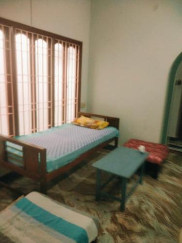 a bedroom with two beds and a table and a window at Villa Butterfly Studio in Pondicherry