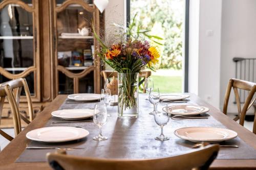 a table with plates and glasses and a vase of flowers at Gite Amélie, Sauna, Spa au coeur des Vosges in Housseras