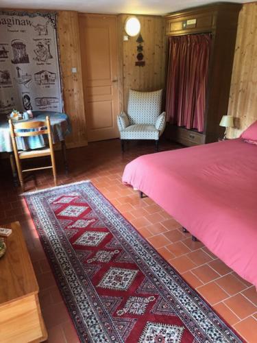 a bedroom with a pink bed and a red rug at Manoir du Val Harangt in Mardilly