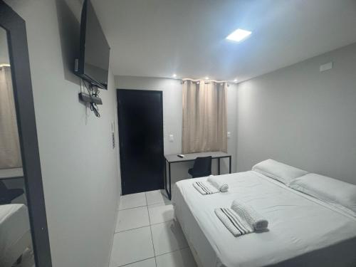 a white bedroom with a bed and a desk at BSH FLATS - Melhor custo benefício in Campina Grande
