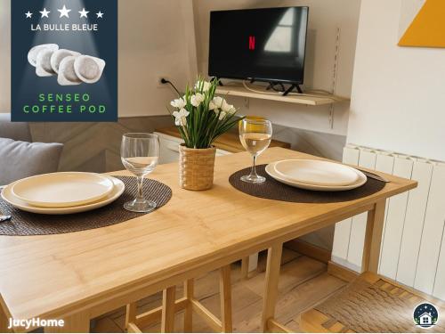 - une table en bois avec 2 assiettes et des verres à vin dans l'établissement La Bulle Bleue, à Berck-sur-Mer