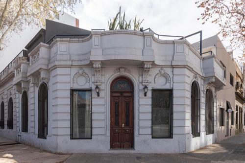 un bâtiment blanc avec une porte marron dans une rue dans l'établissement Fliphaus Villa Nicaragua 5900 - Stylish 5 Bd House Hollywood, à Buenos Aires