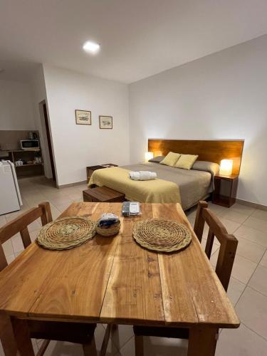 a room with a wooden table and a bed at Nono Huasi Departamentos in Cafayate