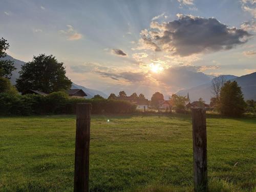 a sunset over a field with two wooden posts at atHOME Appartements in Rattendorf