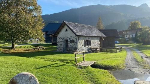 a small stone building on a field with a house at atHOME Appartements in Rattendorf