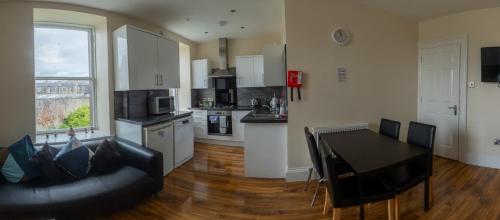 a living room with a black couch and a kitchen at 3 Bedroom Apartment with castle views in Edinburgh