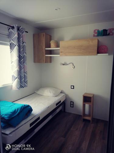 a small bedroom with a bed and a window at MH 556 - Océan Landes in Saint-Julien-en-Born