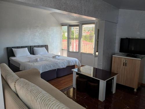 a bedroom with a bed and a tv and a couch at mano guest house in Batumi