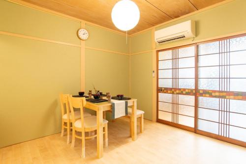 una sala da pranzo con tavolo, sedie e orologio di 100 square meters up to 11 people Namba Direct Bus 3 mins JR Osaka Loop Line Station 8 mins Train to Namba 12 mins, USJ 30 mins Kyoto Nara OK ad Osaka