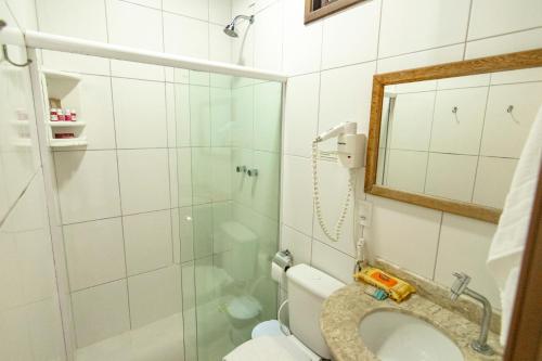 a bathroom with a toilet and a glass shower at Pousada Aroeira in Morro de São Paulo