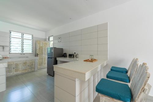 a kitchen with a counter with chairs and a refrigerator at Hibiscus in Diani Beach
