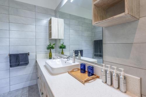 a white bathroom with a sink and a mirror at Hibiscus in Diani Beach