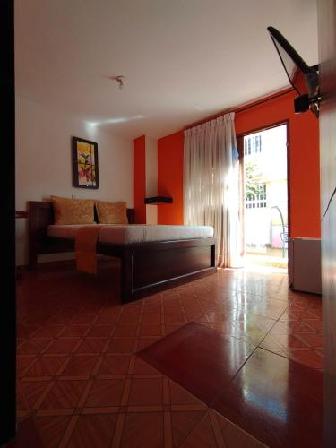 a bedroom with a bed in a room with orange walls at Hotel ZONA ROSA MARINILLA in Marinilla