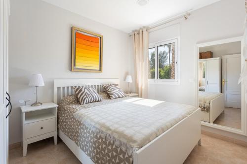 a white bedroom with a bed and a mirror at SeaBreezeHeaven - Sea View Apartment, Pool & Spacious Terrace with BBQ - 50m from Sant Pol Beach in Sant Feliu de Guixols