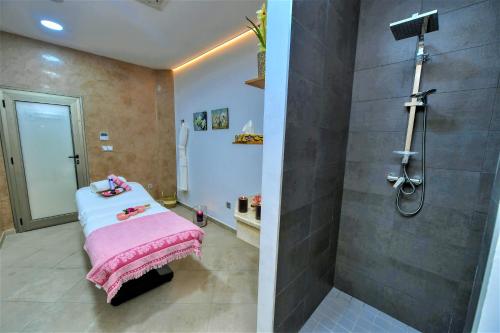 ein Badezimmer mit Dusche und ein Bett mit einer rosa Decke in der Unterkunft Hotel Falcon Thalassa Resort & SPA in Aïn El Turk
