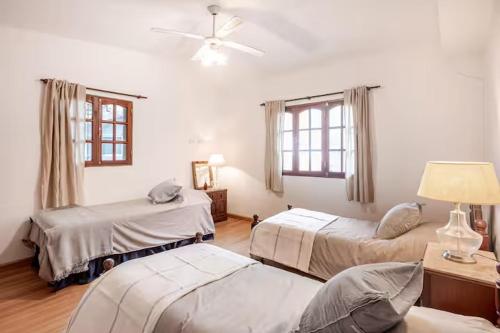 a bedroom with two beds and a ceiling fan at Hermosa Casa V. General Belgrano in Villa General Belgrano