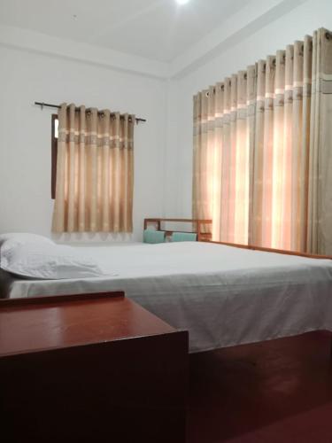 a bedroom with a bed and a window with curtains at White house in Diyatalawa