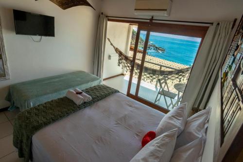 a room with a bed and a view of the ocean at Pousada Aroeira in Morro de São Paulo