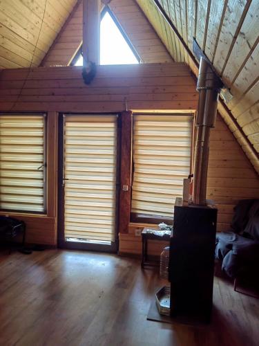 a room with three windows with blinds in a attic at Cabanele lui Sem in Oeștii Ungureni