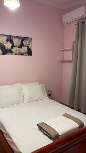 a bed with white sheets and a painting on the wall at HeidiHouse in Patra