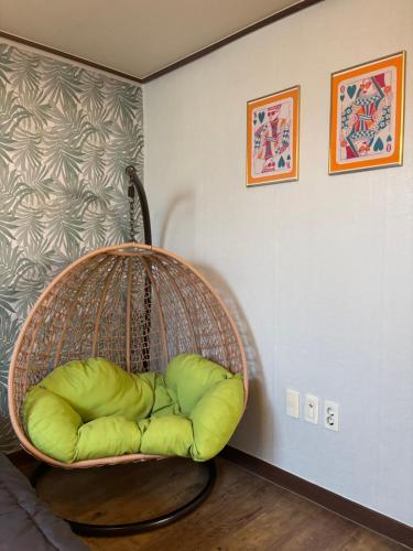 a rattan chair with a green pillow in a room at Daegu Stay Hoya in Daegu