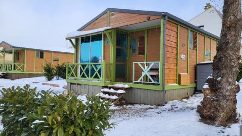une maison verte et en bois avec de la neige au sol dans l'établissement Le petit Chalet de Saillagouse - Location tout confort à la montagne, à Saillagouse
