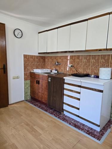 a kitchen with white cabinets and a clock on the wall at Vikendica ENSO Roge Serbia in Požega