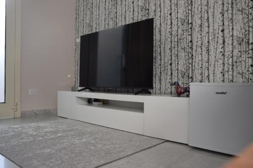 una TV a schermo piatto su un centro di intrattenimento bianco di Eden Borbonico a Caserta