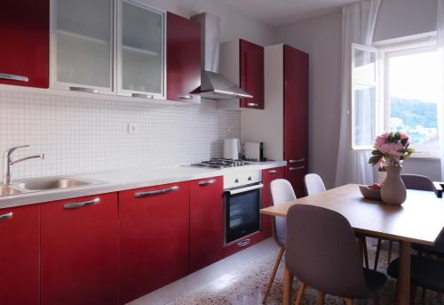 una cocina con armarios rojos y una mesa con un jarrón de flores en NIDO Apartments, en Pučišća