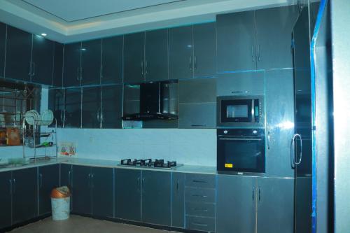 a blue kitchen with a stove and a microwave at Golf View Lodges in Abbottabad