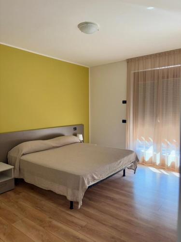 a bedroom with a bed and a yellow wall at Terrazza sul Parco in Comano Terme