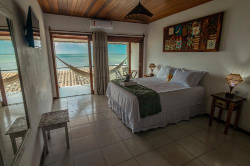 a bedroom with a bed with a view of the ocean at Pousada Aroeira in Morro de São Paulo