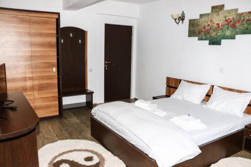 a bedroom with a bed and a desk and a table at Pensiunea de la Rau Moieciu de sus in Moieciu de Sus