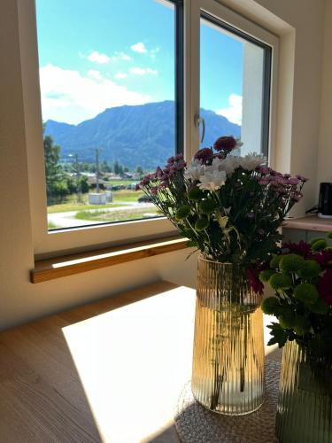 two vases with flowers sitting on a table in front of a window at Servus in der Wiesenstrasse in Ruhpolding
