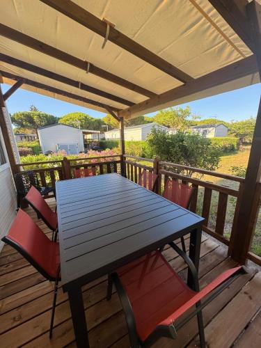 a wooden table and chairs on a deck at Nouveau bungalow No 575 Camping 4 étoiles Lac des Rêves in Lattes