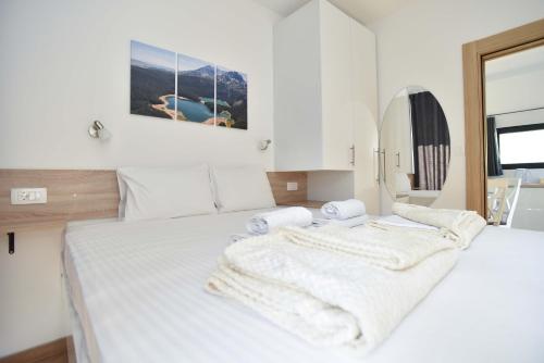 a white bedroom with two beds with towels on them at Apartments Jadranski Biser in Čanj