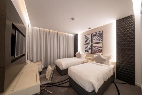 a hotel room with two beds and a television at DAMAC Royal Two Bedroom Apartment Al Olaya in Riyadh