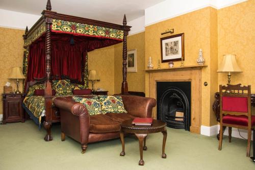 a bedroom with a couch and a bed and a fireplace at Beechwood Hotel in North Walsham
