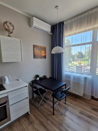 a kitchen with a black table and chairs and a window at SunCoast terrace apartment in Saulkrasti