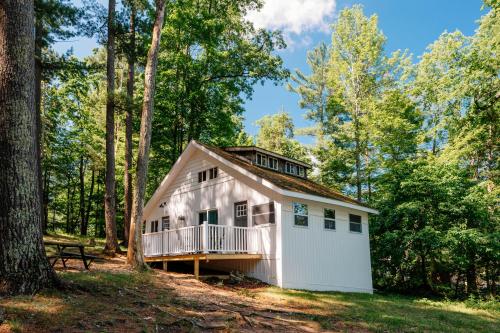 a small white cottage in the woods with a bench at Arbutus l Bonfires l Beach l Lakefront l Pets OK! in Traverse City