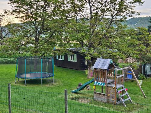 patio con parque infantil con tobogán y cama elástica en Chalet Vert 10 min walk to Argentat city center, en Argentat
