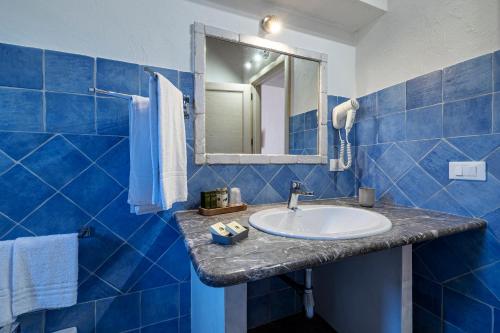 a blue tiled bathroom with a sink and a mirror at Casale La Macina - Hotel, Scopello in Scopello