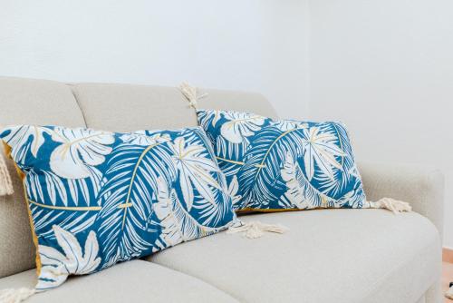 a couch with two blue and white pillows on it at Delizioso Appartamento San Teodoro Lu Fraili in San Teodoro