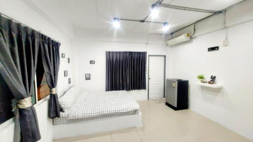 Una habitación blanca con una cama y una ventana. en Mata'home, en Pattaya South