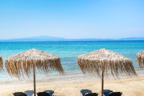 a group of straw umbrellas and chairs on a beach at Chrissi Seastar in Skala Sotiros