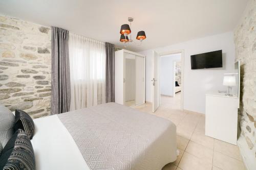 a bedroom with a white bed and a stone wall at Chrissi Seastar in Skala Sotiros